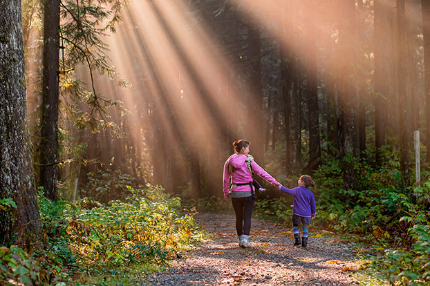 Nainen ja lapsi kävelevät syksyisessä metsässä